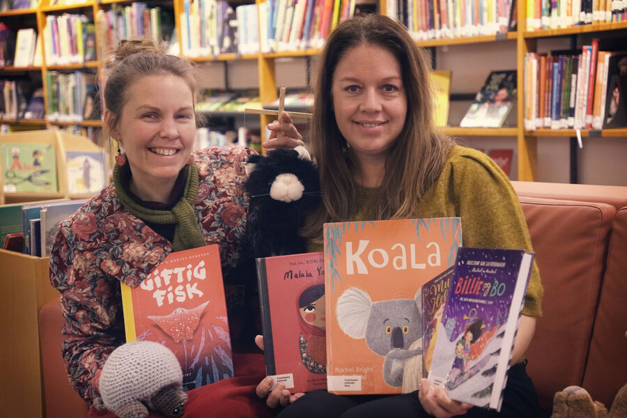 Bilde av bibliotekarene Ann-Charlott og Ingvild som viser frem et lite utvalg med barnebøker